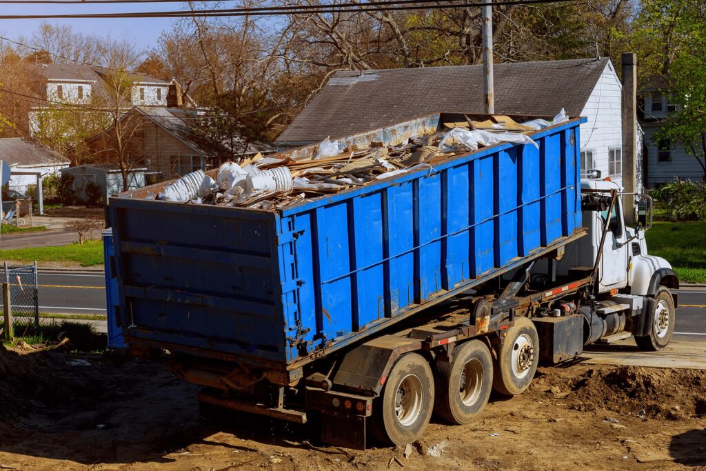 Large blue dumpster being transported by a haul-away truck.